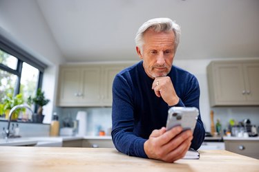 Senior man at home using a mobile app on his cell phone