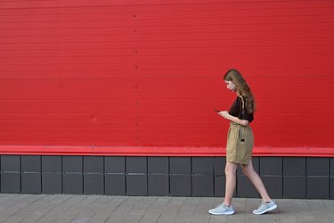 Portrait of a young student reading a message on a mobile phone, a stylish pretty girl chatting on a mobile phone while walking down the street disorder, disorder, technology, disease,dependent