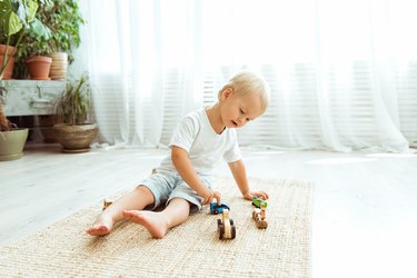 Preschool boy play with ecological wooden cars. Educational toys for preschool and kindergarten child. Child at home or daycare