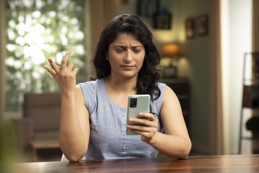 Indian young woman using phone at home, stock photo