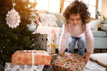 Girl, placing Christmas presents under the Christmas tree