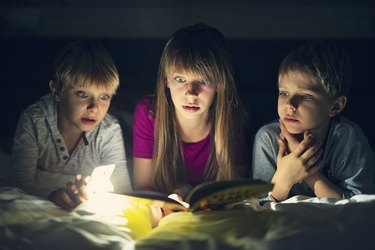 Kids reading a book with scary stories at night