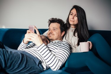 Jealous woman peeking her husband while texting