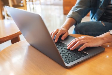 a woman working and typing on laptop computer keyboard on the table