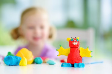 Cute little girl having fun with colorful modeling clay at a daycare. Creative kid molding at home.
