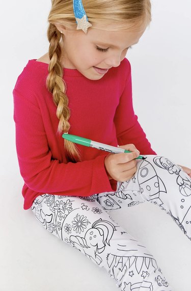 Girl coloring on white pants