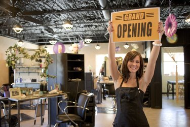 Beauty salon employee holding a grand opening sign