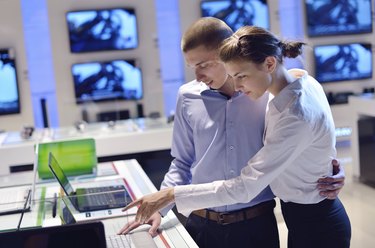 couple in consumer electronics store buying laptop