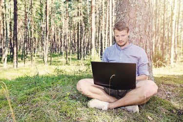young man working with his laptop outdoors