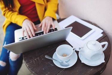 Woman hands with laptop tablet and tea outdoors in cafe