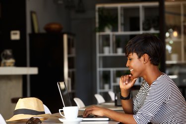 Smiling young african american woman working on laptop