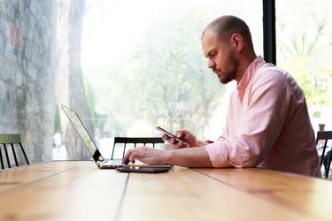 Young hipster busy using smart phone at office desk