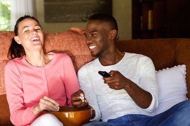 Happy young couple enjoying watching movie at home