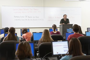 Rear view of a group of students sitting in front of computer monitors