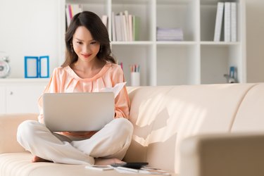 Smiling woman sitting on the couch with laptop