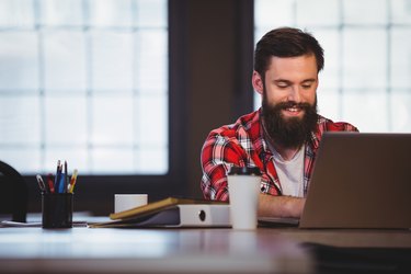 Hipster smiling while working on laptop