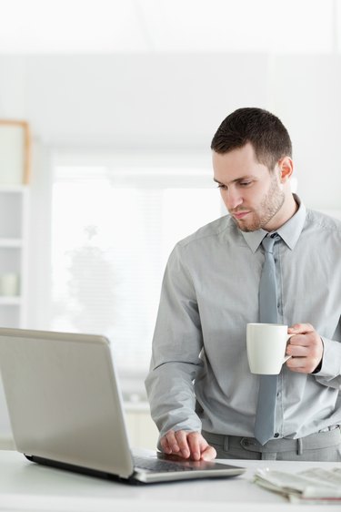 Portrait of a businessman using a notebook while drinking tea