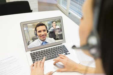 Businesswoman in the office on videoconference with headset, Skype