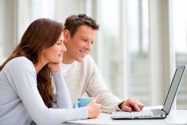 Couple using a laptop and smiling