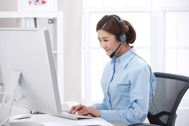 Young business lady wearing headset in front of laptop