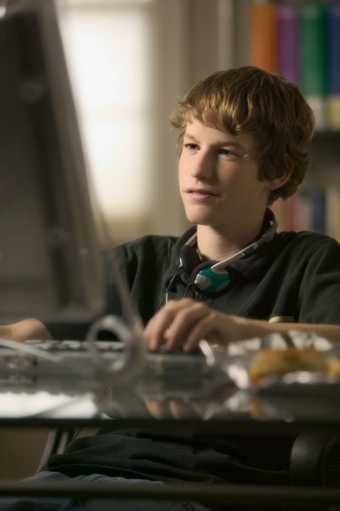 lifestyle portrait of a teenage male as he sits at his computer and works