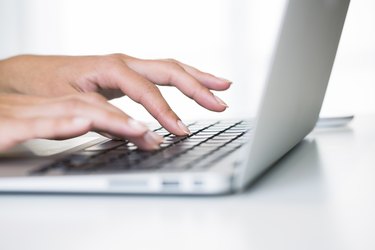 Woman hands typing on a laptop keyboard