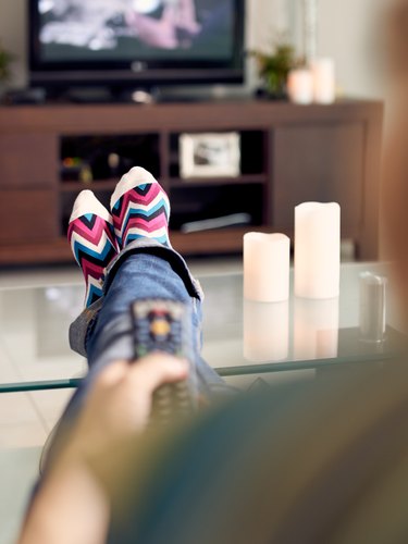 Woman Relax On Sofa Watching Film On TV With Remote