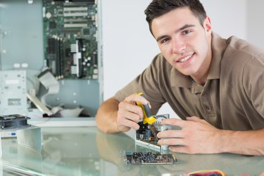Handsome smiling computer engineer repairing hardware with pliers