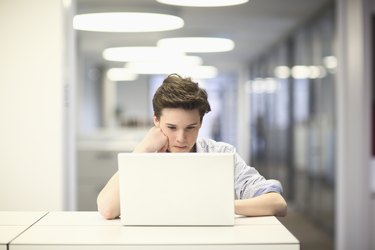 Teenage boy using laptop in office