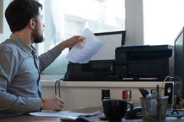 Handsome businessman scanning and printing document in office