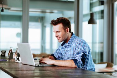 Young man at cafe typing on laptop