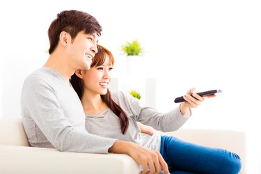 happy young couple watching tv in living room
