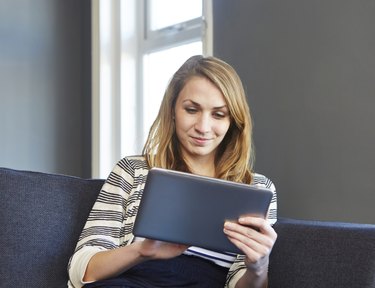 Girl using digital tablet on sofa