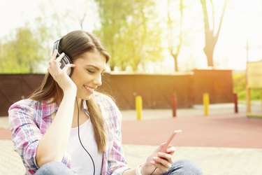 Young woman with headphones in park listening to music