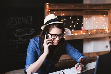 Beautiful hipster woman taking notes at modern office
