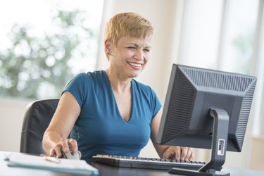 Happy Businesswoman Using Computer At Desk