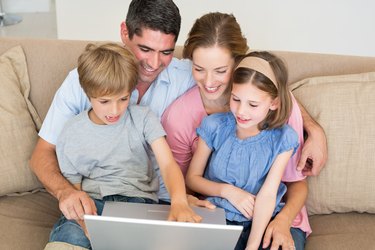 Loving family using laptop together on sofa