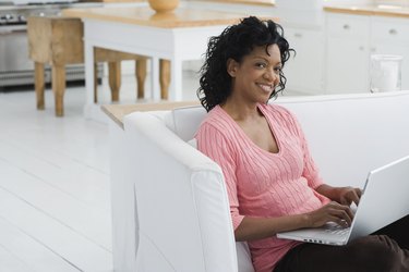 Woman sitting on couch and using laptop computer