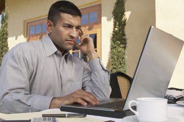 Mid adult man working on laptop at outdoor cafe table