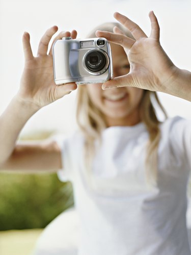 Young Girl Takes a Picture With a Digital Camera, Focus on the Camera in the Foreground