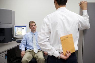 Man hiding envelope from co-worker