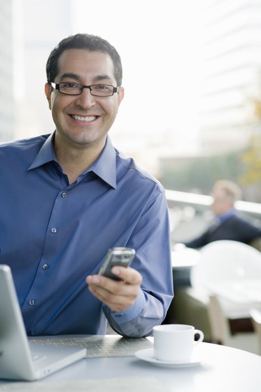 Smiling business man with phone and computer.