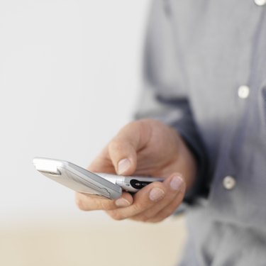 Man text messaging using mobile phone, close-up, studio shot