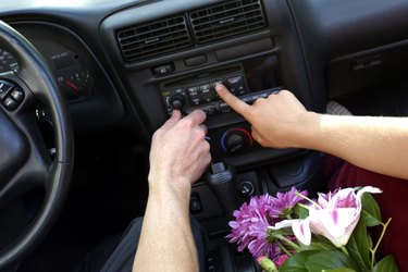 Close-up of two hands pressing buttons to adjust the car stereo.