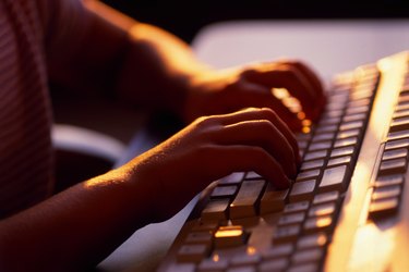 Clasp of child's hands typing on keyboard