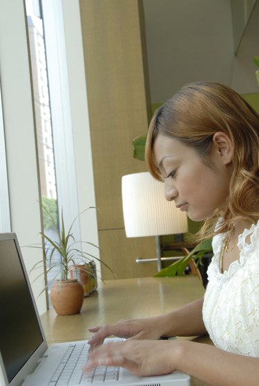 Young woman using laptop in cafe, blurred motion