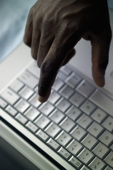 Man's hand above laptop computer, close-up, part of, selective focus