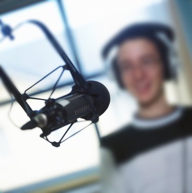 close-up of a microphone in a recording studio with a man wearing headphones; blurred
