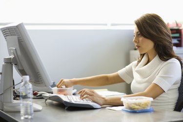 Young businesswoman eating lunch at desk