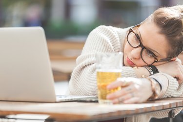 Tired girl with beer and computer in London